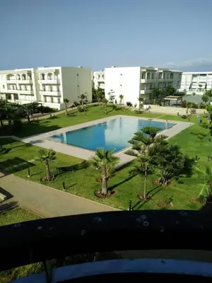 a view of a swimming pool with palm trees and buildings at Bahía Golf Beach BOUZNIKA in Bouznika