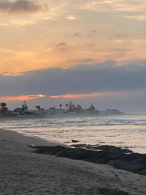 a beach with the ocean and a sunset in the background at Bahía Golf Beach BOUZNIKA in Bouznika