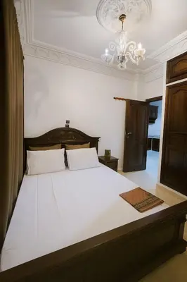 a bedroom with a large white bed with a chandelier at Calme, plage 8 min, tout proche in Temara