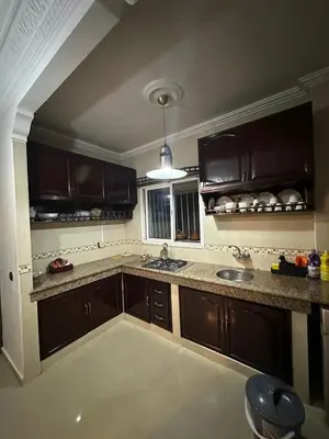 a kitchen with brown cabinets and a sink at Calme, plage 8 min, tout proche in Temara