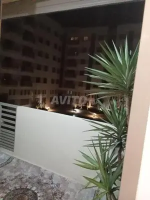 a balcony with two palm trees in a city at night at Zineb in Nouaseur