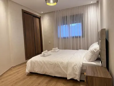 a bedroom with a bed with white sheets and a window at Appartement chic Rabat in Rabat