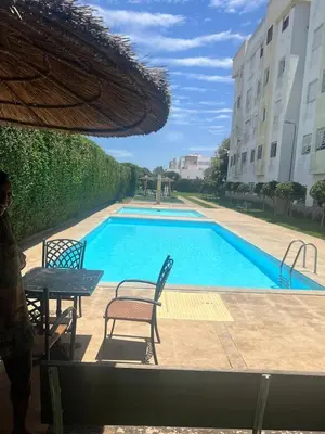 a swimming pool with a table and chairs next to a building at Appartement Cosy & Calme avec Piscine, Tamaris Dar Bouazza in Tamaris