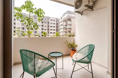 two green chairs and a table on a balcony at 5 min from airport, 1 bedroom, balcony, pools in Nouaceur