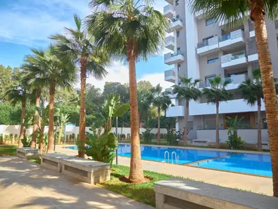 a hotel with palm trees and a swimming pool at Appartement haut standing in Casablanca