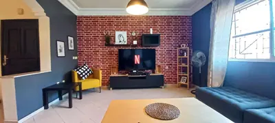 a living room with a brick wall and a tv at Budget-Friendly Apartment Near AirPort in Nouaseur