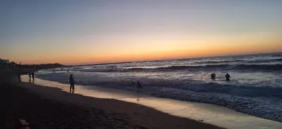 a group of people playing in the waves at the beach at Villa oued cherrat bouznika 3 bedrooms in Bouznika