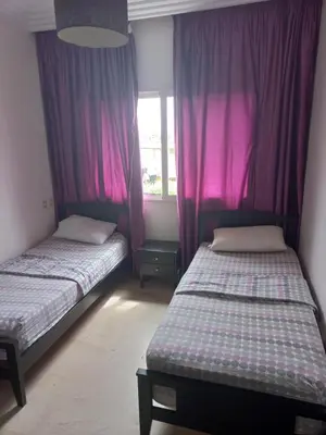 two beds in a room with purple curtains at Berrada in Dar Mohammed Ould Haj Jilali