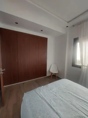 a bedroom with a bed and wooden cabinets and a window at Duplex de Luxe avec Vue Mer a Zenata City-Eco in Aïn Harrouda