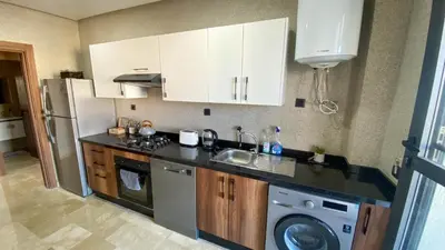 a kitchen with white cabinets and a washer and dryer at Résidence luxueuse avec 5 Piscine A MANSOURIA près de la Mer in O Ben Slimane