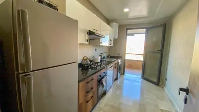 a kitchen with a refrigerator and a stove top oven at Résidence luxueuse avec 5 Piscine A MANSOURIA près de la Mer in O Ben Slimane