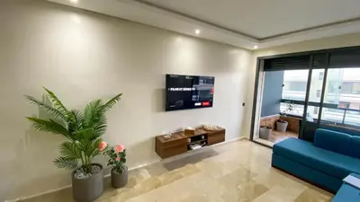 a living room with a blue couch and a tv at Résidence luxueuse avec 5 Piscine A MANSOURIA près de la Mer in O Ben Slimane