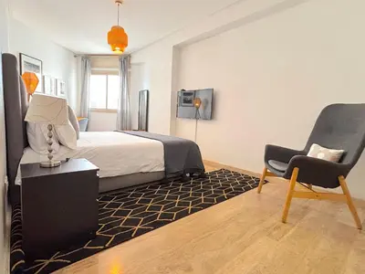 a bedroom with a bed and a chair and a tv at Casa Sahifa in Casablanca