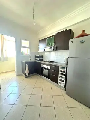 a kitchen with a refrigerator and a tile floor at Appartement avec piscine Bouznika in Bouznika