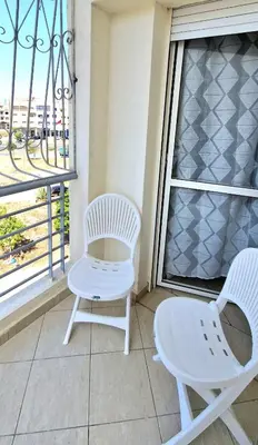 two white chairs sitting on a balcony with a window at Appartement avec piscine Bouznika in Bouznika