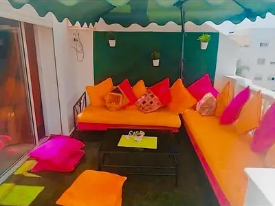 a living room with an orange couch with colorful pillows at Appart avec piscine in Pont Blondin