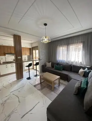 a living room with a couch and a kitchen at Élégance et Confort à Proximité de la Plage in Bouznika