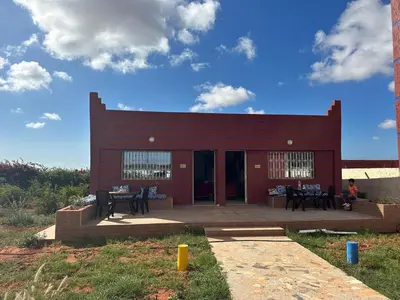 a red building with tables and chairs in front of it at Ferme touristique domaine BENJDYA à HAD SOUALEM in Berrechid
