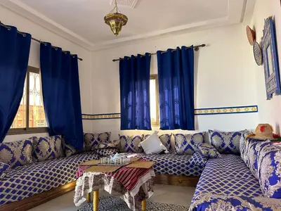a living room with blue curtains and a couch at Ferme touristique domaine BENJDYA à HAD SOUALEM in Berrechid