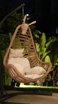 a wicker swing chair with pillows in a garden at appart luxueuse a rabat hay riad avec piscine in Rabat