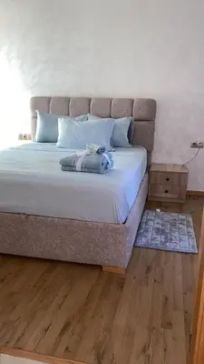 a large bed in a bedroom with a wooden floor at Two bedroom Apartment in Bouznika Beach in Bouznika