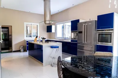 a kitchen with blue cabinets and a stainless steel refrigerator at Bouskoura park in Bouskoura