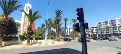 a traffic light on a street with palm trees and buildings at Confort & Style à Mohammedia parc in Mohammedia