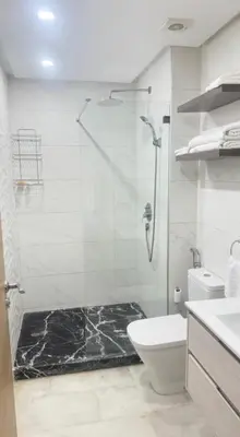 a bathroom with a glass shower and a toilet at appartement de luxe au rez de jardin avec piscine privative in Tamaris