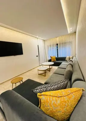 a living room with a couch and a tv at appartement de luxe au rez de jardin avec piscine privative in Tamaris