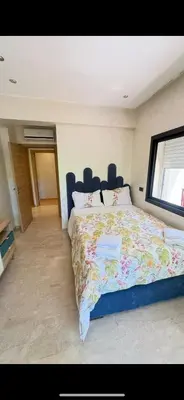 a bedroom with a large bed with a floral bedspread at appartement de luxe au rez de jardin avec piscine privative in Tamaris