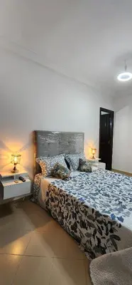 a bedroom with a large bed with two tables and two lamps at Appartement à côté de mosquée Hassan 2 et marina shopping in Casablanca