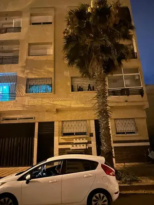 a white car parked in front of a building with a palm tree at Appartement sidi rehal in Casablanca
