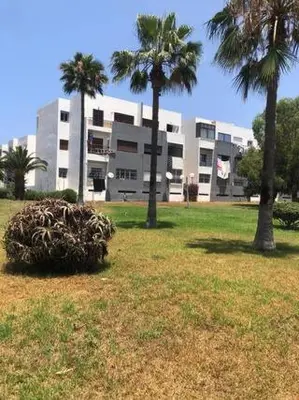 a building with two palm trees in a field at Chambre cosy en bord de mer in Mohammedia
