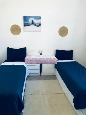two beds in a room with a table between them at Chambre cosy en bord de mer in Mohammedia