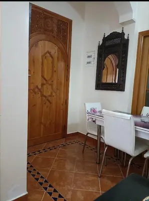 a room with a wooden door and a table and chairs at Kasbah de bouznika, style Marrakech avec jardin et piscine in Kasba Bou Hamira