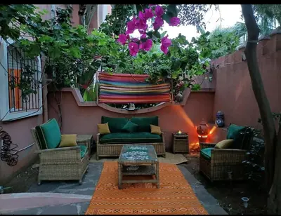 a patio with a couch and chairs and flowers at Kasbah de bouznika, style Marrakech avec jardin et piscine in Kasba Bou Hamira