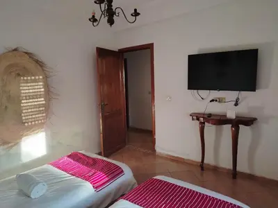 a room with a tv and a bed and a table at Appartement aéroport Mohammed 5 in Deroua