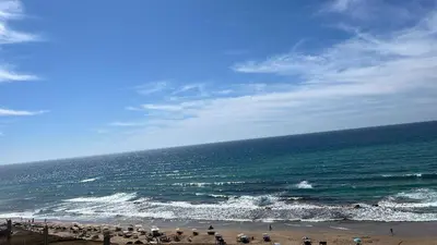 a group of people standing on a beach near the ocean at Bel appartement centre Asilah proche de la mer in Aïn Harrouda