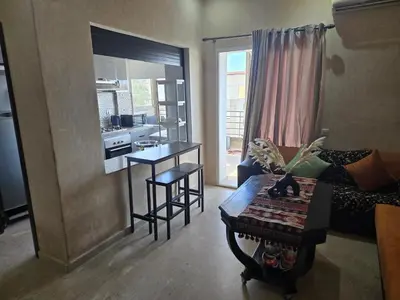 a living room with a table and a kitchen at Les perle de tamaris in Dar Mohammed Ould Haj Jilali