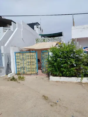 a building with a gate with a umbrella on it at Cosy cabanon plage david in Kasba Bou Hamira