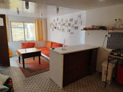a kitchen and living room with a couch and a table at Cosy cabanon plage david in Kasba Bou Hamira