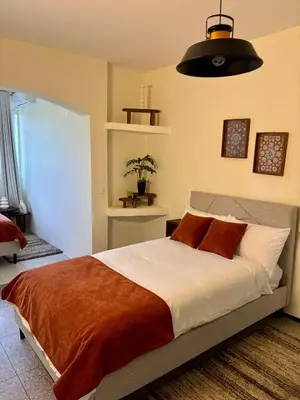 a bedroom with a large bed with orange and white pillows at Cozy Stay with Hassan Tower View in Rabat