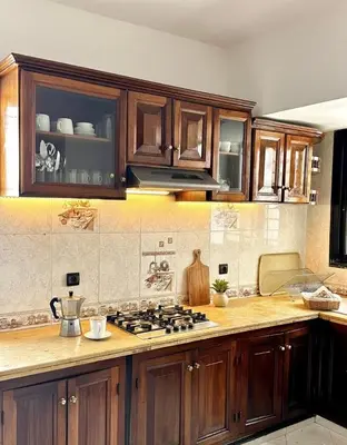 a kitchen with wooden cabinets and a stove top oven at Grand Appartement à Louer à Agdal, à Deux Pas de la Gare in Rabat
