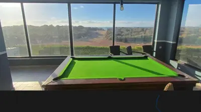 a green pool table in front of a window at Blue Beach Residence Balnéaire pour familles in Sidi Rahal