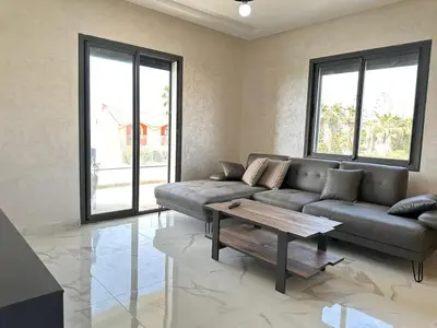 a living room with a couch and a coffee table at Sidi Rahal Appt raffiné, pieds dans l'eau in Sidi Rahal