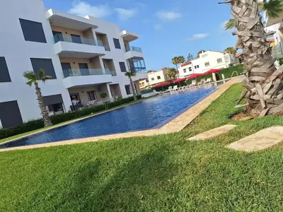 a swimming pool in front of a building at Sidi Rahal Appt raffiné, pieds dans l'eau in Sidi Rahal