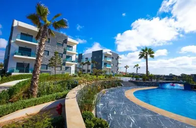 a resort with a swimming pool and palm trees at Appartement Moderne très bien équipé pour familles seulement- Résidence Garden Bay Dar Bouazza in Tamaris