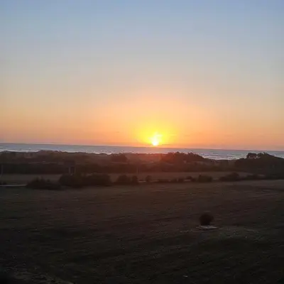 a sunset over a field with the ocean at Appartement Moderne très bien équipé pour familles seulement- Résidence Garden Bay Dar Bouazza in Tamaris