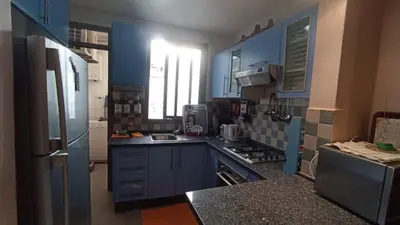 a kitchen with blue cabinets and a refrigerator at Appartement moderne proche de la plage avec piscine in Skhirat