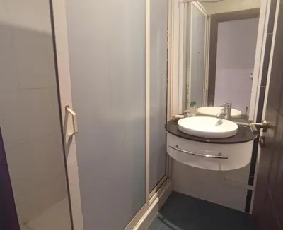 a bathroom with a sink and a glass shower at Appartement moderne proche de la plage avec piscine in Skhirat